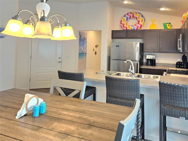 kitchen featuring dark brown cabinets, sink, appliances with stainless steel finishes, hardwood / wood-style floors, and pendant lighting