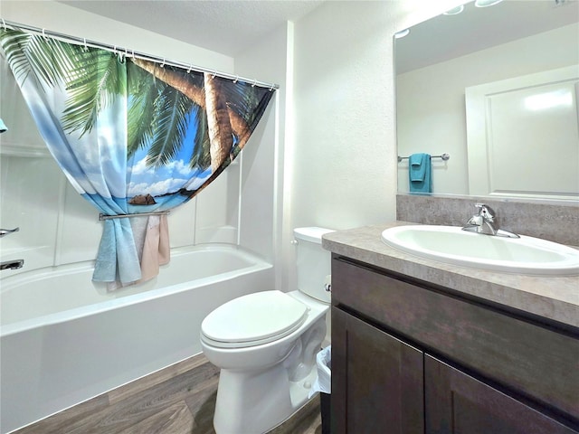 full bathroom featuring wood-type flooring, shower / tub combo with curtain, oversized vanity, toilet, and a textured ceiling