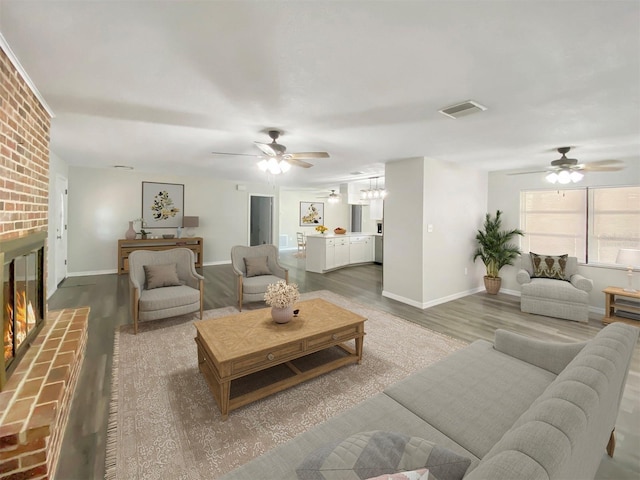 living room featuring hardwood / wood-style flooring, ceiling fan, and a brick fireplace