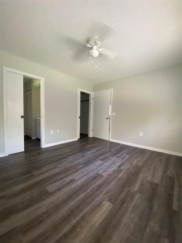 unfurnished bedroom with dark hardwood / wood-style floors, ceiling fan, ensuite bathroom, and a textured ceiling