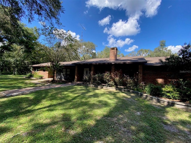 1921 Smitty Rd, Weirsdale, FL 32195 - back of property featuring a lawn, a chimney, and brick siding