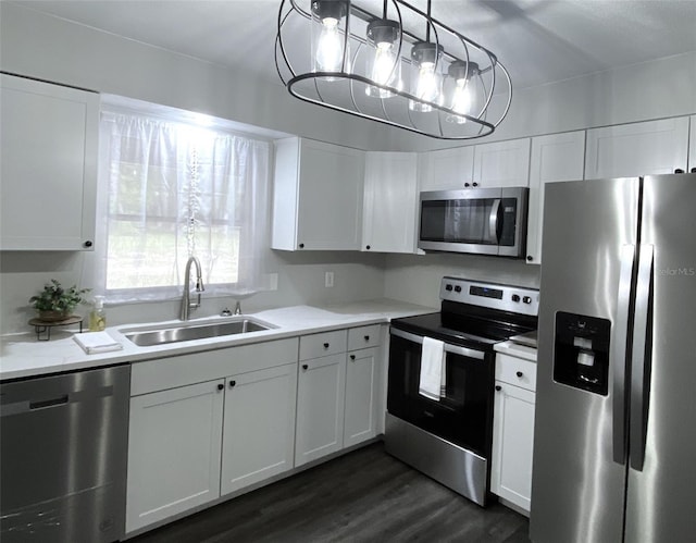 kitchen with white cabinetry, sink, hanging light fixtures, stainless steel appliances, and dark hardwood / wood-style floors