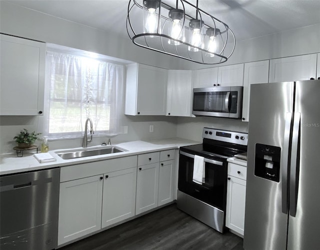 1921 Smitty Rd, Weirsdale, FL 32195 - kitchen with stainless steel appliances, white cabinetry, dark wood-style flooring, light countertops, and decorative light fixtures