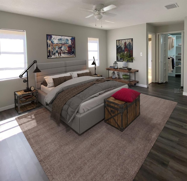 bedroom with ceiling fan, dark wood-type flooring, and multiple windows