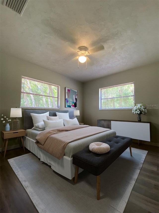 bedroom featuring dark hardwood / wood-style floors, multiple windows, and ceiling fan