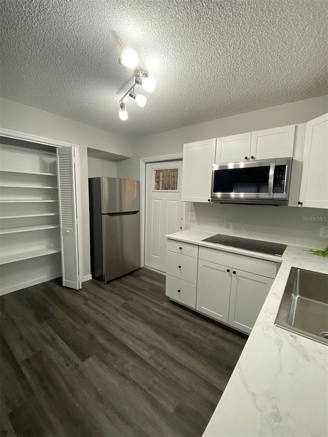 1921 Smitty Rd, Weirsdale, FL 32195 - kitchen with stainless steel appliances, a textured ceiling, white cabinets, dark wood-style flooring, and light stone countertops