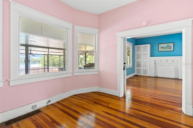 spare room with hardwood / wood-style floors and a brick fireplace