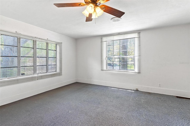 empty room with dark colored carpet and ceiling fan