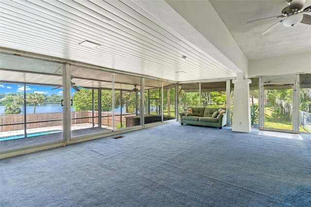 unfurnished sunroom with ceiling fan, a water view, and plenty of natural light