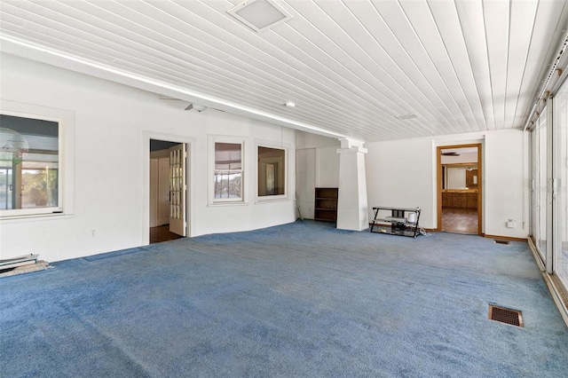 unfurnished living room featuring decorative columns, a wealth of natural light, and carpet