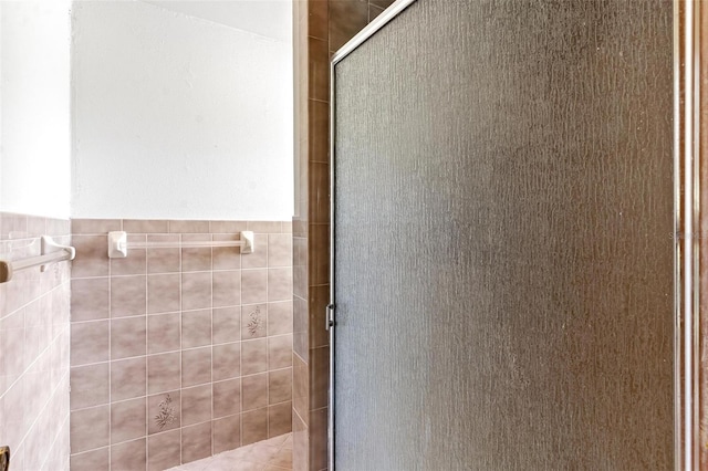 bathroom featuring walk in shower and tile walls