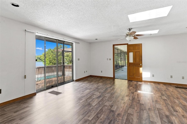 unfurnished room featuring a skylight, ceiling fan, and dark hardwood / wood-style flooring