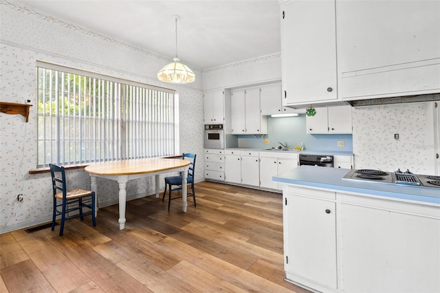 kitchen featuring white cabinetry, pendant lighting, light wood-type flooring, and appliances with stainless steel finishes