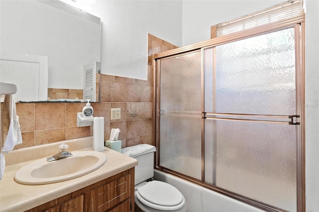 full bathroom with toilet, combined bath / shower with glass door, tile walls, and vanity