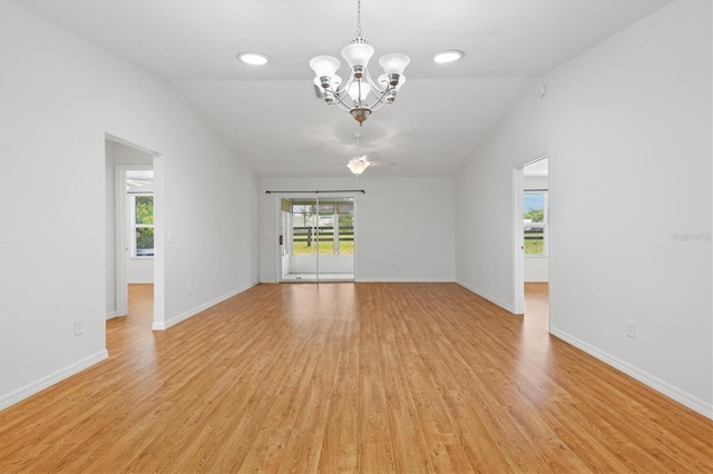 empty room featuring light wood-type flooring, vaulted ceiling, and a notable chandelier