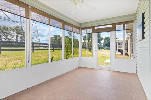 unfurnished sunroom featuring ceiling fan and a healthy amount of sunlight