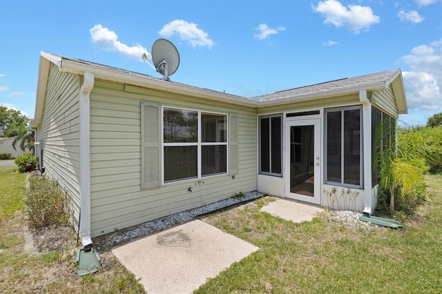 back of property with a lawn and a sunroom