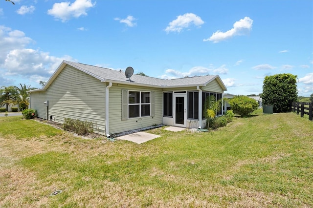 back of property with a sunroom and a yard