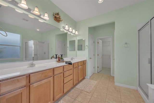 bathroom featuring vanity with extensive cabinet space, double sink, an enclosed shower, and tile flooring