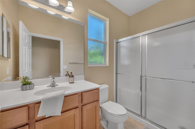 bathroom featuring a shower with door, toilet, tile floors, and large vanity