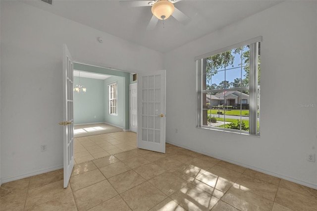 unfurnished bedroom featuring ceiling fan with notable chandelier, multiple windows, french doors, and light tile flooring