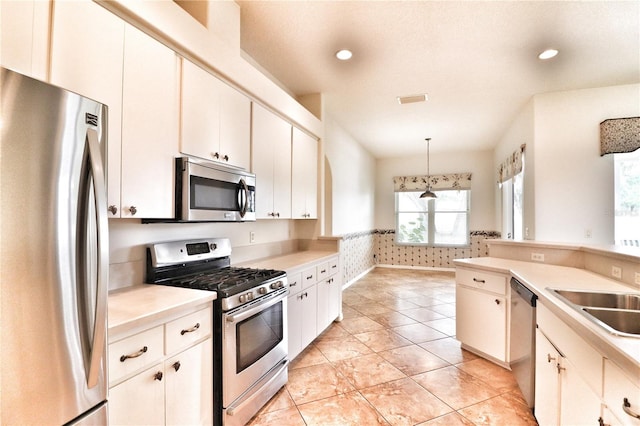 kitchen with white cabinets, appliances with stainless steel finishes, and decorative light fixtures