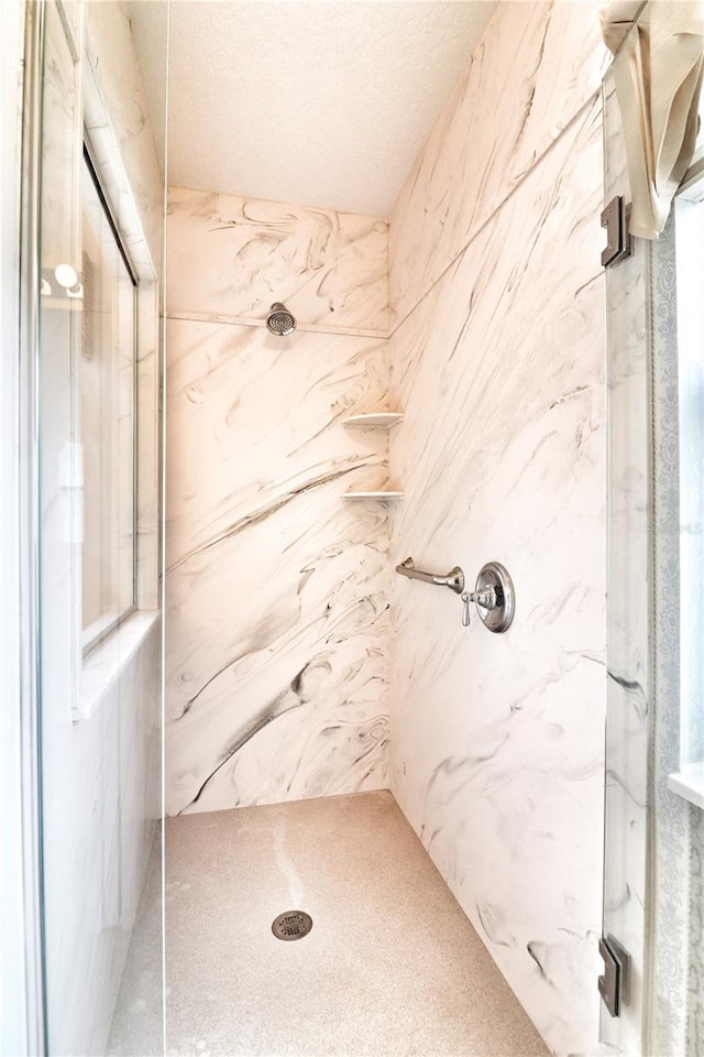 bathroom with a tile shower and a textured ceiling