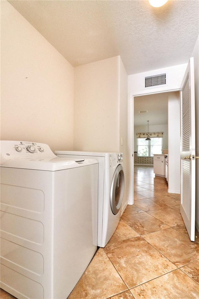 washroom featuring a textured ceiling and washing machine and clothes dryer