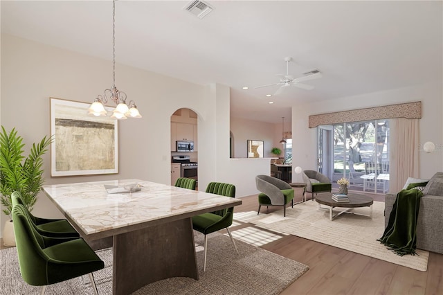 dining room with wood-type flooring and ceiling fan with notable chandelier