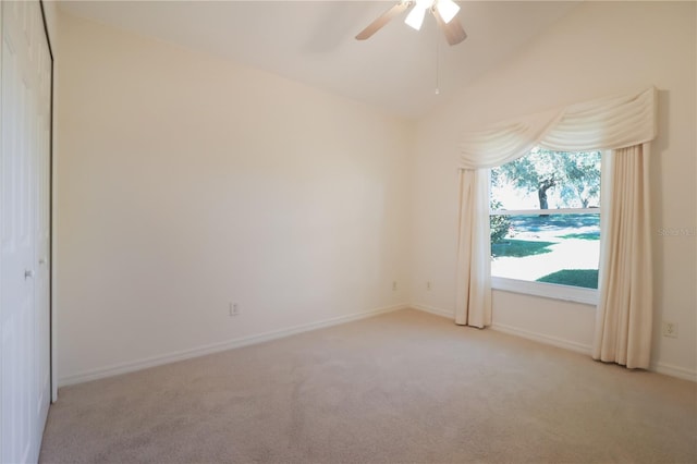 carpeted spare room featuring ceiling fan and vaulted ceiling