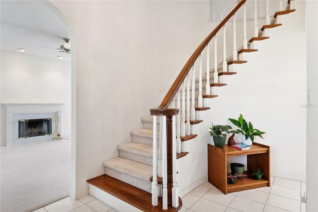 stairs with ceiling fan and light carpet