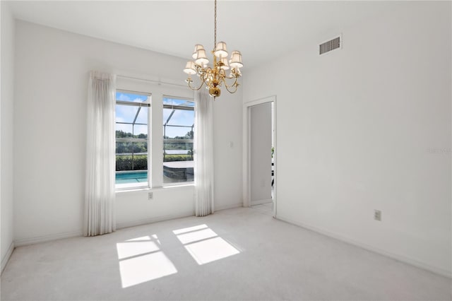 carpeted spare room with a chandelier