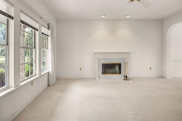 unfurnished living room featuring a wealth of natural light, light carpet, and a premium fireplace