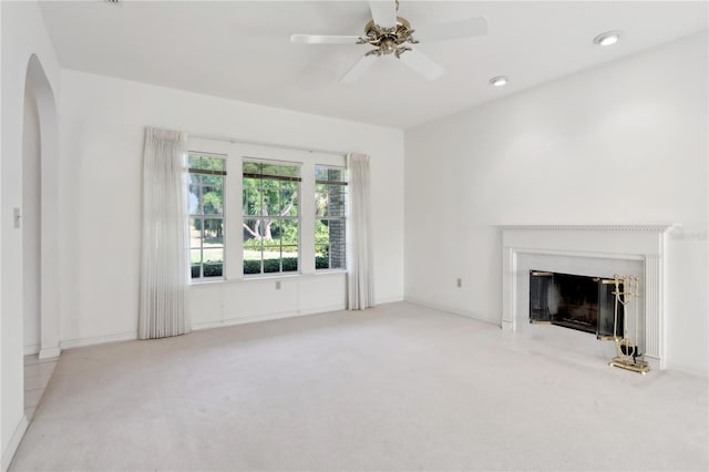 unfurnished living room with light colored carpet, ceiling fan, and a fireplace