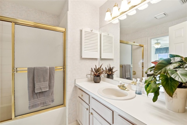 bathroom featuring vanity with extensive cabinet space, bath / shower combo with glass door, and ceiling fan