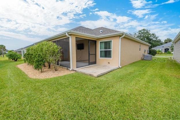 rear view of property with a yard, a patio area, and a sunroom