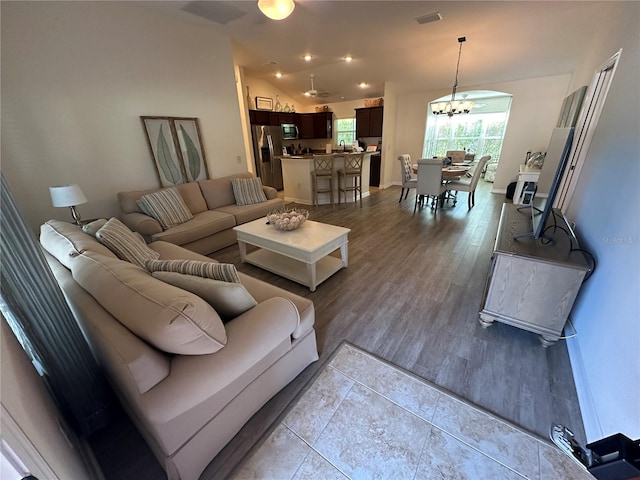 living room featuring light hardwood / wood-style flooring, sink, vaulted ceiling, and an inviting chandelier