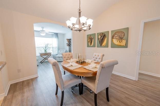 dining space with hardwood / wood-style flooring, lofted ceiling, and an inviting chandelier