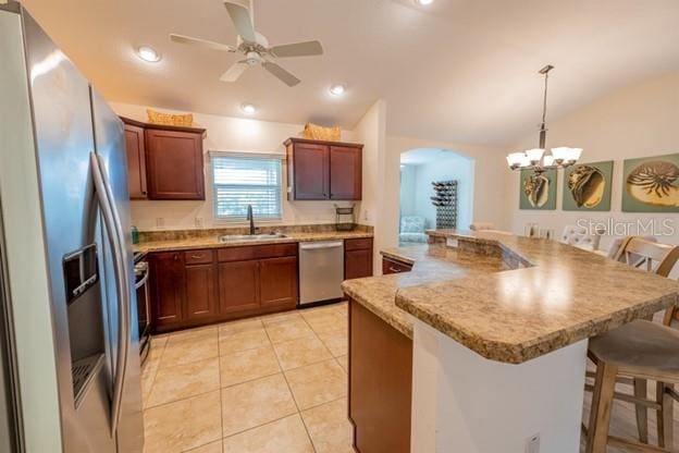 kitchen with sink, a breakfast bar area, stainless steel appliances, decorative light fixtures, and vaulted ceiling