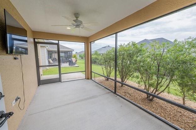 unfurnished sunroom featuring ceiling fan