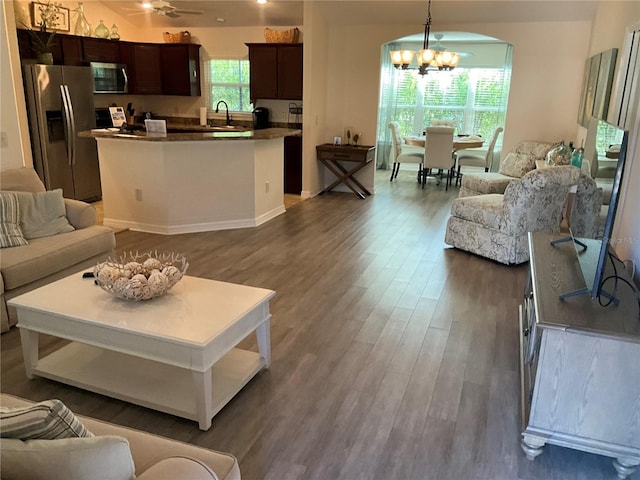 living room featuring a healthy amount of sunlight, dark hardwood / wood-style floors, sink, and a chandelier