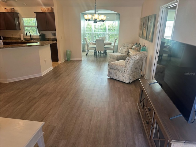 living room with sink, an inviting chandelier, and dark hardwood / wood-style flooring