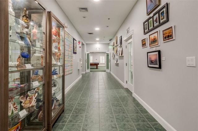 hall featuring visible vents, dark tile patterned floors, and baseboards