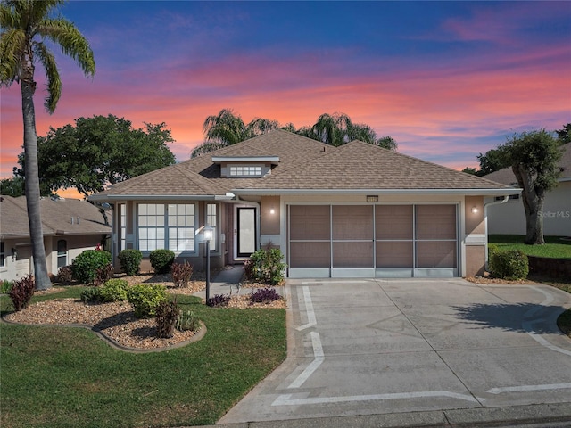 view of front of house with concrete driveway, a lawn, an attached garage, and stucco siding