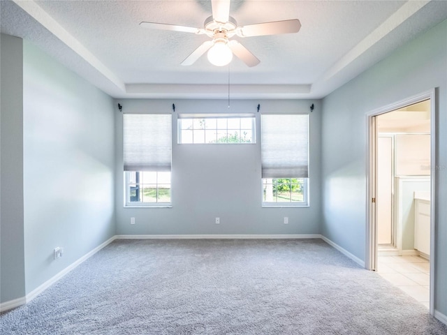 unfurnished room with light carpet, ceiling fan, a textured ceiling, and a healthy amount of sunlight