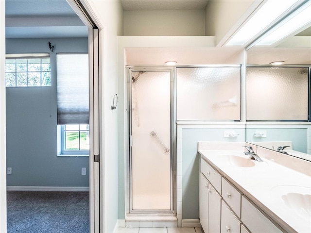 full bath with a shower with door, a sink, baseboards, and double vanity