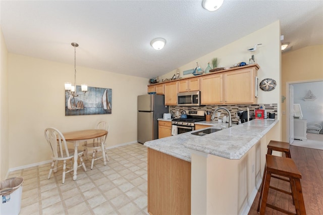 kitchen with kitchen peninsula, stainless steel appliances, backsplash, vaulted ceiling, and sink