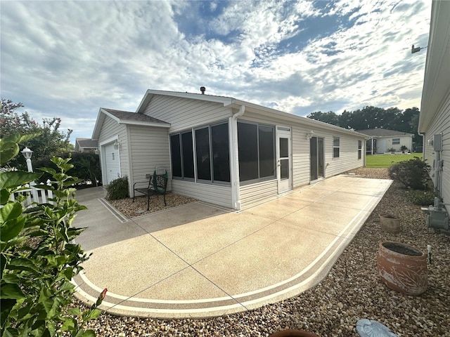 rear view of property featuring a patio and a garage