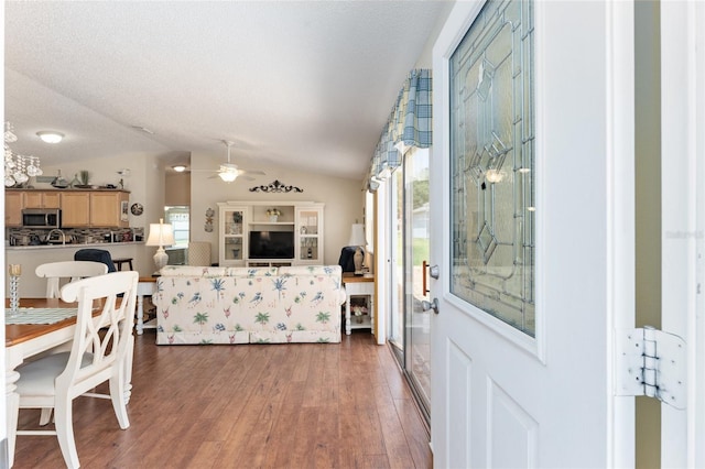 foyer featuring ceiling fan, vaulted ceiling, dark wood-type flooring, and a textured ceiling