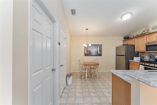 kitchen with backsplash, pendant lighting, an inviting chandelier, a textured ceiling, and stainless steel appliances